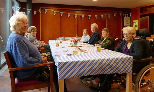 Bewohner:innen des Pflegeheims sitzen am festlich dekorierten Tisch.